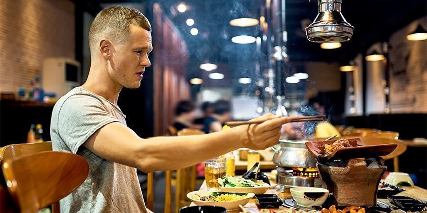 Mann spiser med spisepinner på restaurant i Vietnam
