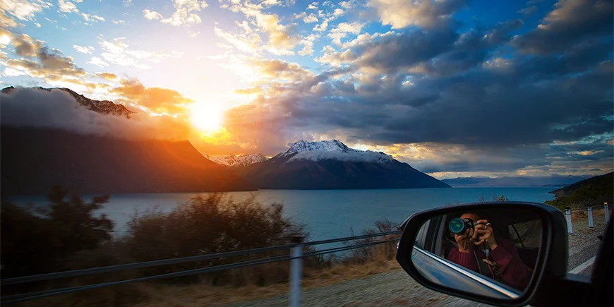 Mann som tar et bilde ut av vinduet ved Lake Wakatipu på Sørøya i New Zealand