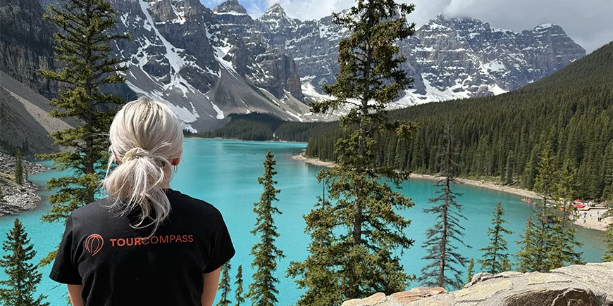 Kvinne i TourCompass-T-skjorte som ser ut over vannet ved Lake Louise i Canada
